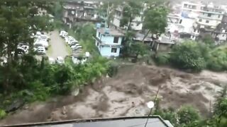 Buildings and cars are swept away with a huge stream of flood in Himachal Pradesh, India