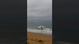 Skimboarder catches a wave at the beach #shorts