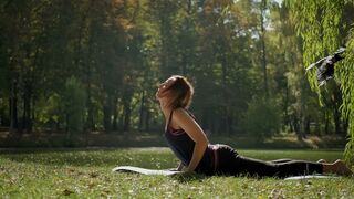 Woman Practicing Yoga Stretching Exercise Outdoors in Sunny Day